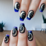 Diseño de uñas con lunas y estrellas en fondo azul oscuro degradado
